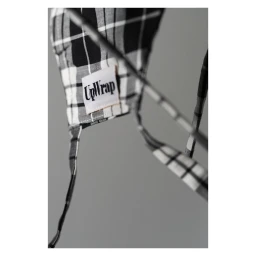 Close-up of black and white plaid fabric with a branded UpWrap label and dangling ties against a grey backdrop