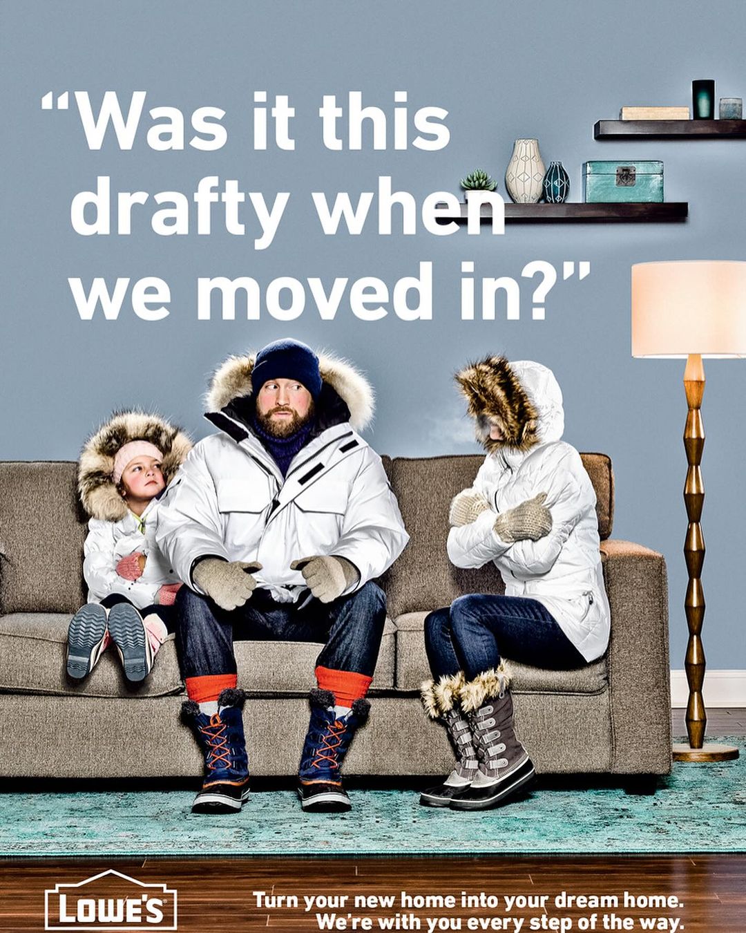 Family wearing winter coats and boots sitting on a couch, with a lamp and shelves in the background. Lowe's logo visible in the foreground.