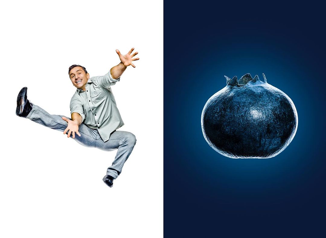 Man in mid-air pose next to a single blueberry against a blue background, contrasting action and macro fruit photography.