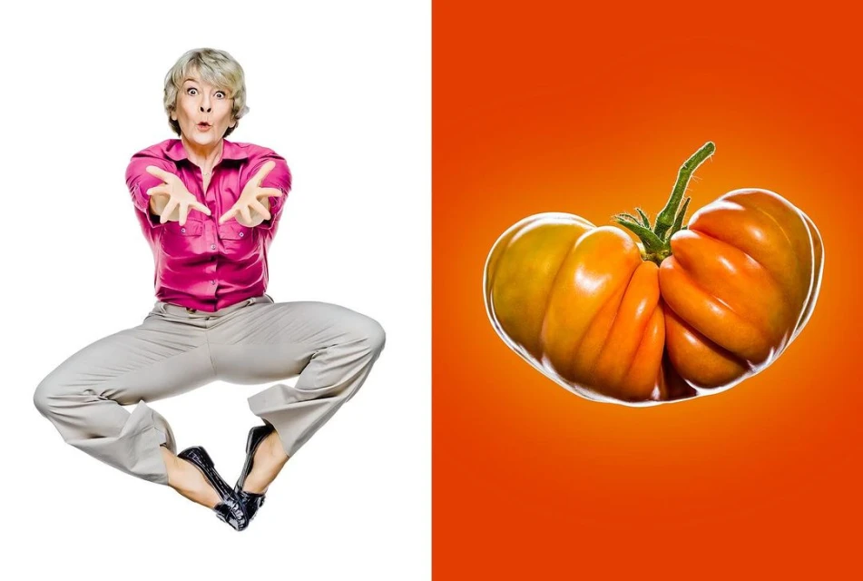 Mature woman jumping with outstretched arms on white, paired with an orange heirloom tomato on an orange backdrop in bright light.