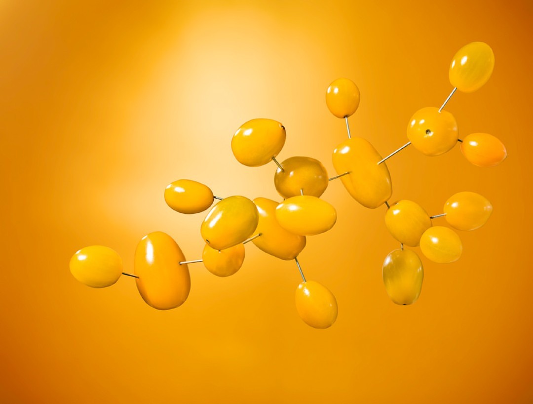 Abstract molecular structure of yellow cherry tomatoes on skewers against a graduated golden background. Food and science concept.