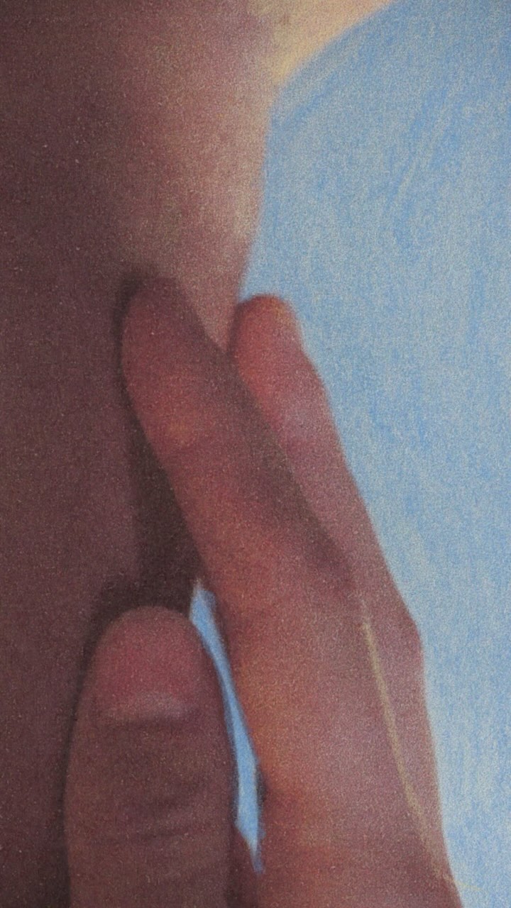 Close-up of a human hand and part of a face against a light blue background.