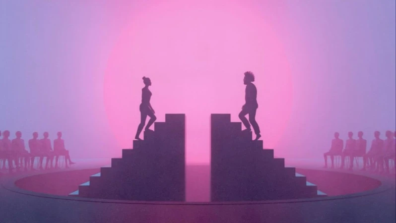 Silhouetted figures ascend stairs on either side of a circle stage, with an audience, against a pink and purple gradient background.