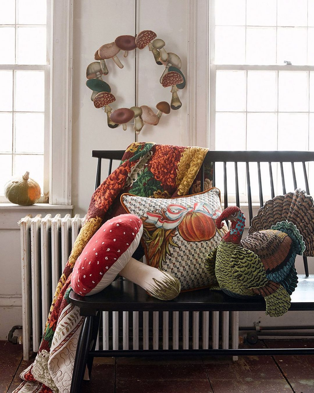 Thanksgiving decor featuring a bench with decorative pillows shaped like mushrooms and turkeys, a quilt, and a mushroom wreath.