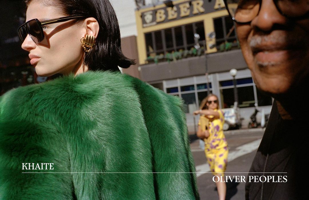 Fashion ad featuring a woman in a green fur coat and sunglasses, with a man and a cityscape in the background.