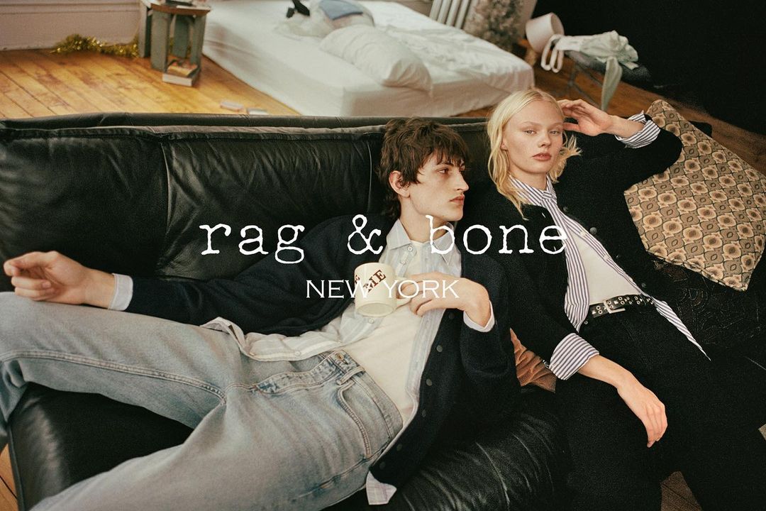 Fashion ad featuring a casually posed couple on a black leather sofa, with the 'rag & bone NEW YORK' logo prominently displayed.