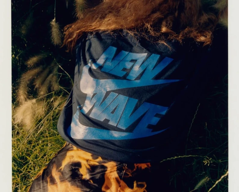 Overhead shot of a person in a Nike tee shirt in a field of tall grass with sunlit highlights and shadow play on their clothing.
