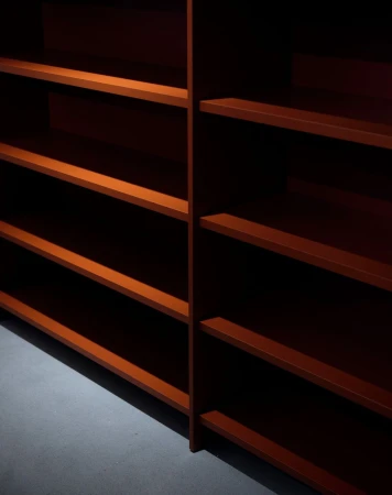 Empty shelves with red-brown wood finish in an indoor space; the shelves are evenly spaced on a light grey floor.