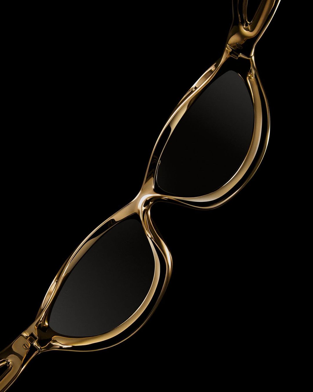 Stylish gold-framed sunglasses with dark lenses against a stark black background, sleek design, and luxurious aesthetic for eye protection.