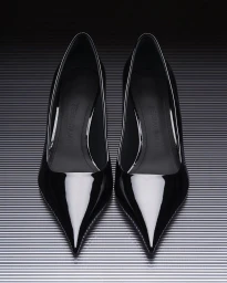 A pair of black patent leather pointed high heels placed on a striped metallic textured background, shot from above.
