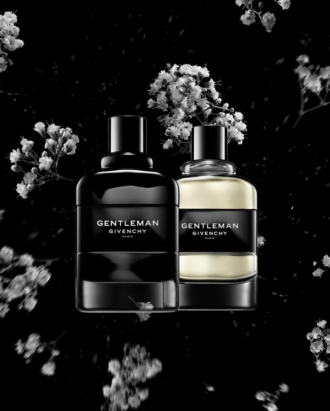 Two Gentleman Givenchy bottles on a black background surrounded by white baby's breath flowers create a luxury beauty advertisement.