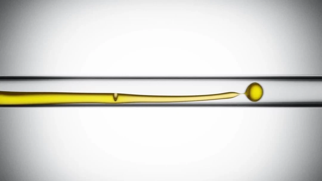 Close-up of a long, thin horizontal glass tube filled with a yellow liquid, featuring a round bubble at the right end.