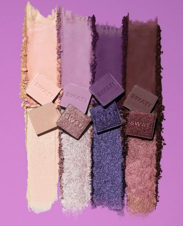 Assortment of colorful eyeshadows and makeup arranged on a lilac background, showcasing different shades from light to dark.