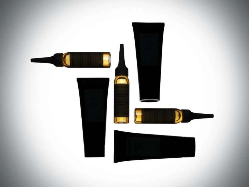 Elevated view of skincare products: amber ampules and black tubes arranged on white backdrop with soft, diffused lighting for beauty advertising.
