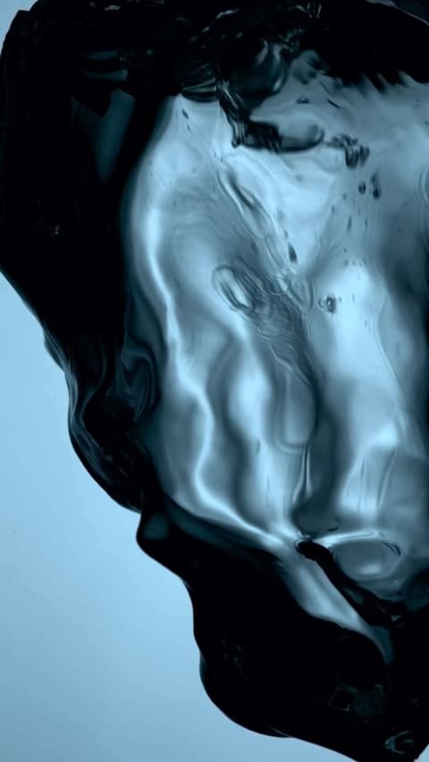 Abstract shot of swirling dark liquid on a gradient blue background, captured in a studio environment for a dynamic visual effect.