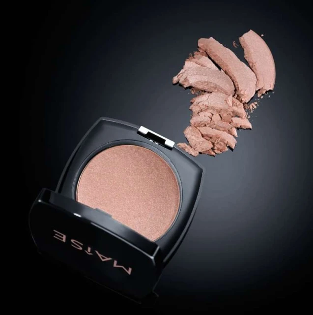 Matte-finish pressed powder in black compact with a metallic shimmer, next to loose cosmetic powder on a dark background.