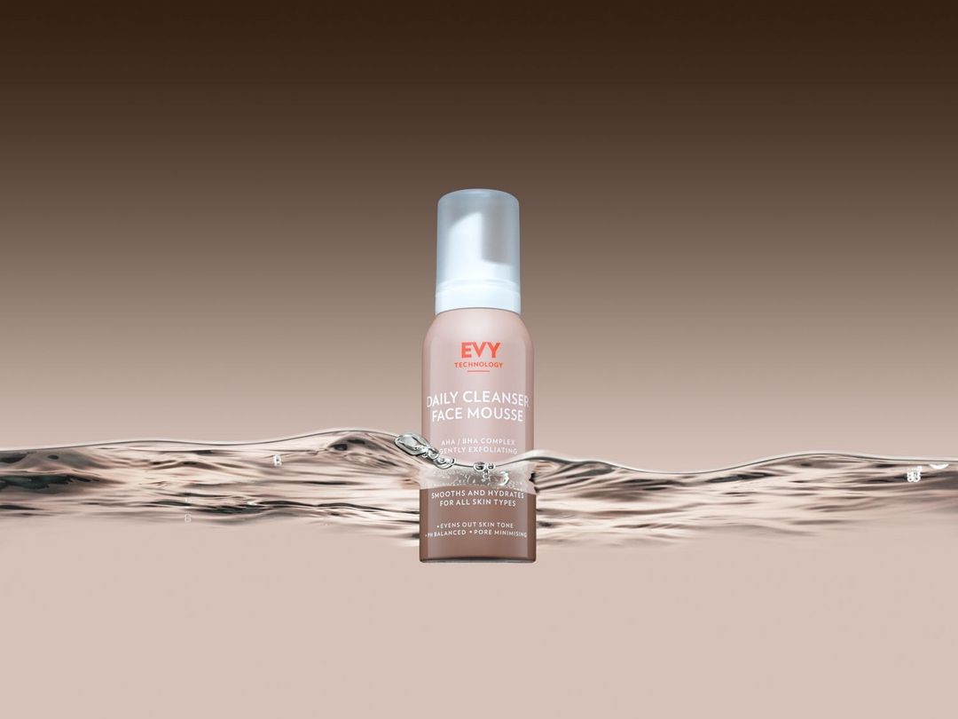 Close-up studio shot of EVY Technology Daily Cleanser Face Mousse, set against a soft gradient background and water ripple effect.