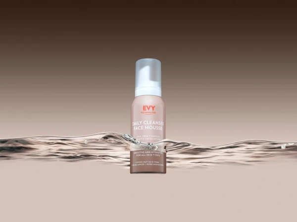 Close-up studio shot of EVY Technology Daily Cleanser Face Mousse, set against a soft gradient background and water ripple effect.