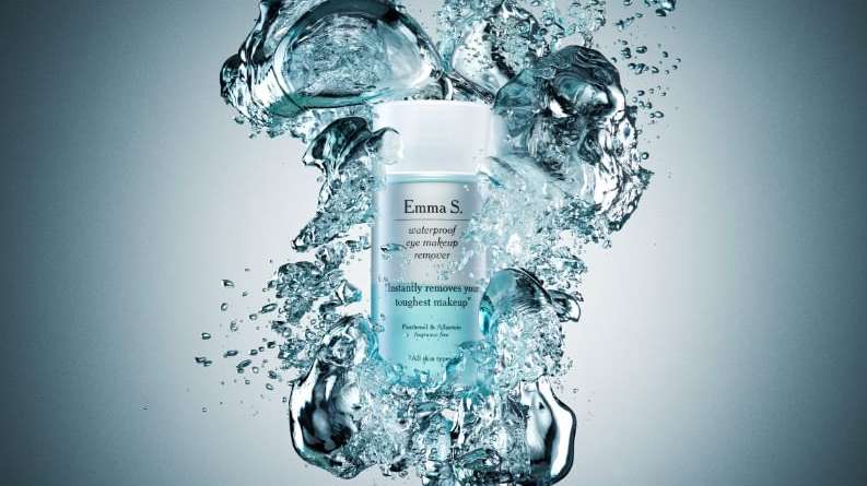 Emma S. waterproof eye makeup remover product shot surrounded by water bubbles on a light blue background in a beauty advertising shot.