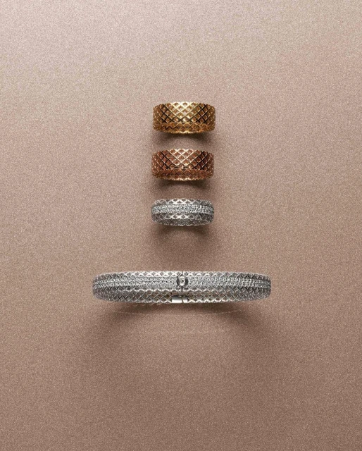 Still life featuring a silver bracelet and gold, rose gold, and silver rings with a woven design arranged on a tan background.