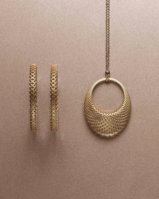 Elegant gold jewelry set featuring hoop earrings and a pendant necklace with intricate lattice design against a neutral backdrop.