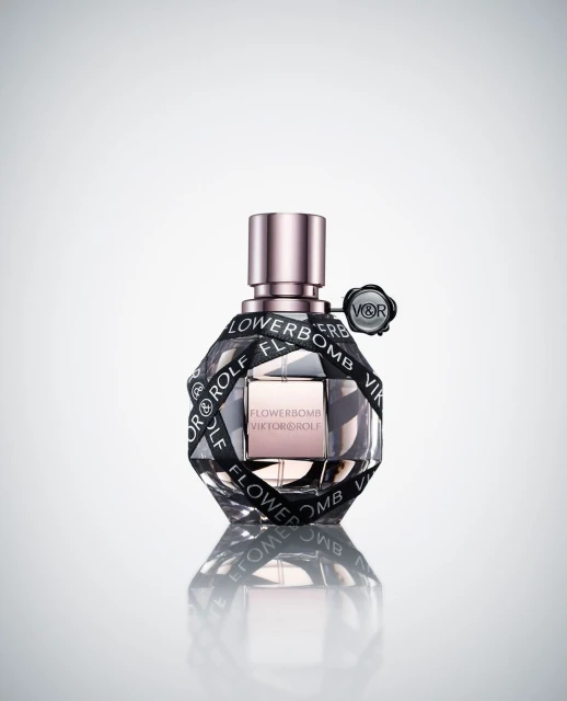 Flowerbomb perfume bottle by Viktor & Rolf, clear glass with black ribbon, set against a gradient white background, product shot.