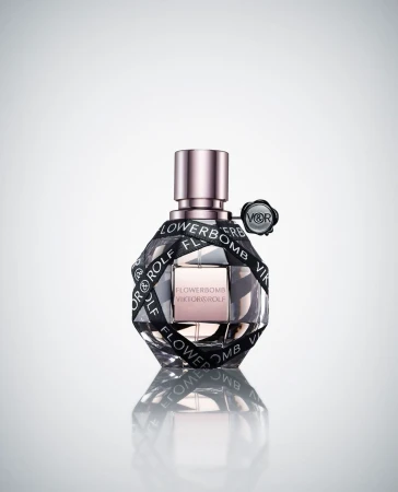Flowerbomb perfume bottle by Viktor & Rolf, clear glass with black ribbon, set against a gradient white background, product shot.