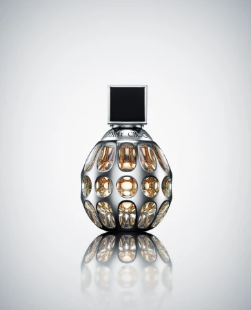 Shiny perfume bottle with a silver spherical body, black square top, and gold liquid inside on a reflective white surface.