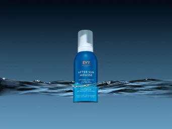 Blue bottle of EVY After Sun Mousse emerging from dark water with ripples against a blue gradient background