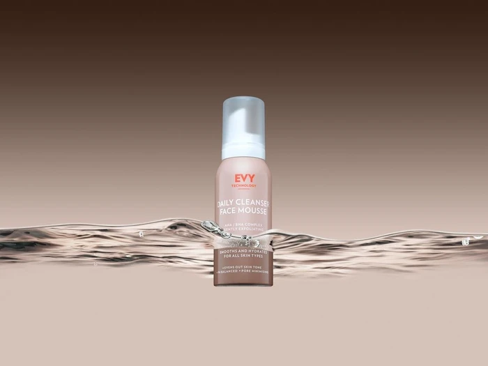 Evy Technology daily cleanser face mousse bottle submerged partially in clear rippling water against gradient background
