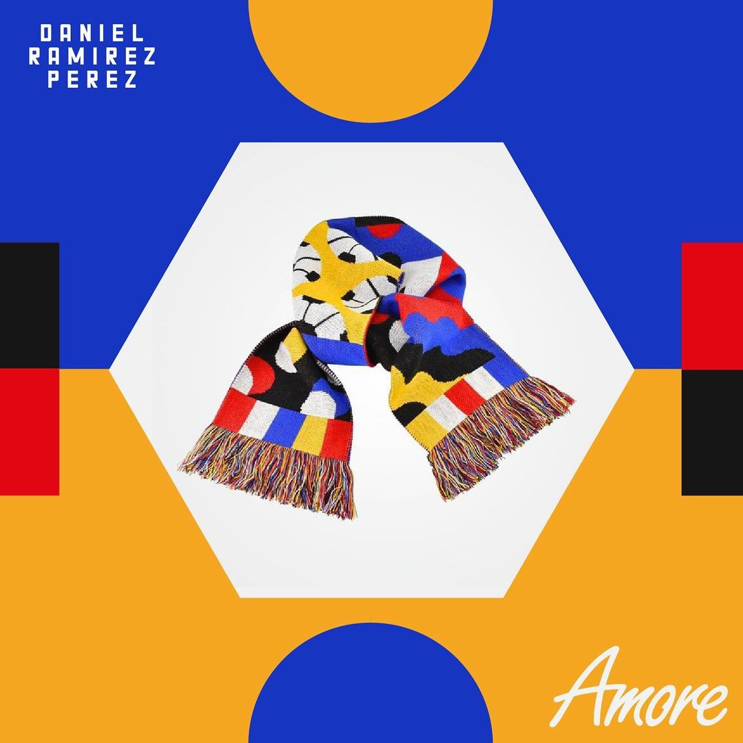 Close-up of a colorful scarf with geometric patterns against a white hexagon, set on a background with blue, red, and mustard yellow.