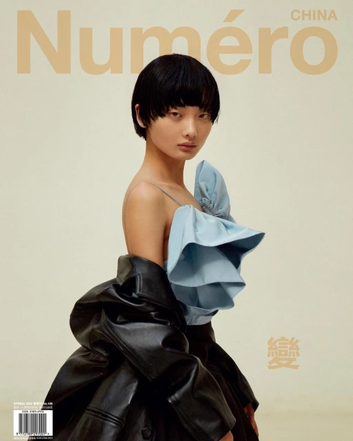 Fashion magazine cover featuring an Asian woman in a blue top and black leather jacket against a light beige background with text.