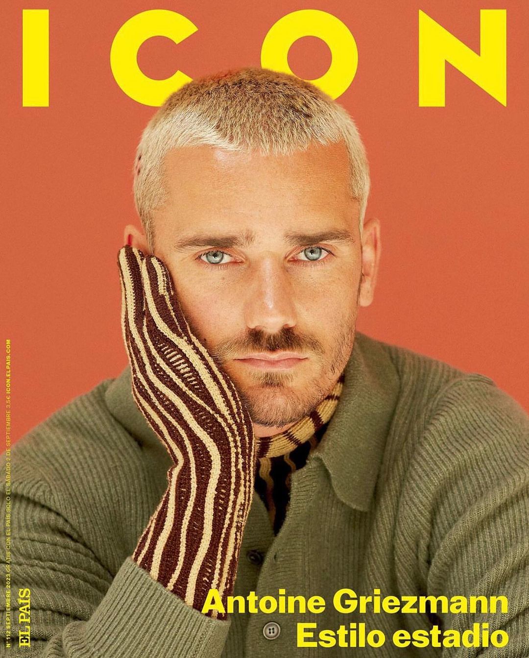Antoine Griezmann poses for a magazine cover, wearing a green sweater and striped glove, with blond hair and a focused expression.