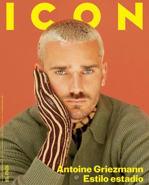 Antoine Griezmann poses for a magazine cover, wearing a green sweater and striped glove, with blond hair and a focused expression.