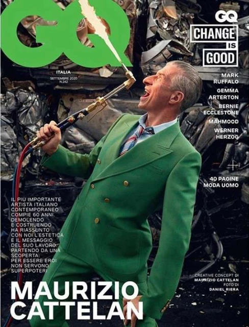 GQ magazine cover featuring Maurizio Cattelan in a green suit holding a blowtorch against a backdrop of crushed metal and the GQ logo.