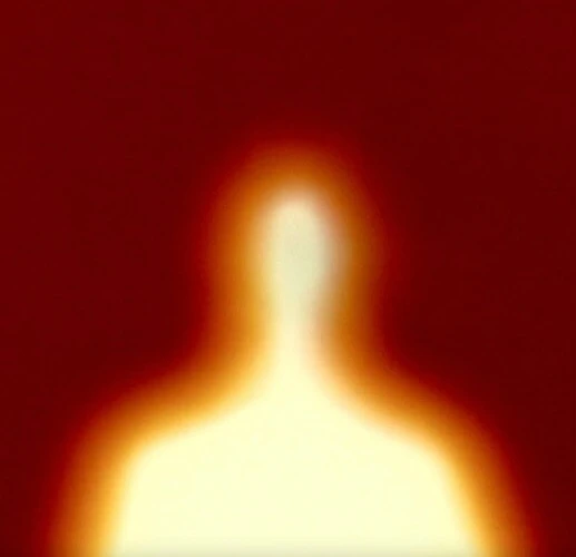 Abstract blurred silhouette of a person against a red background, creating an indistinct figure with a glowing orange aura.