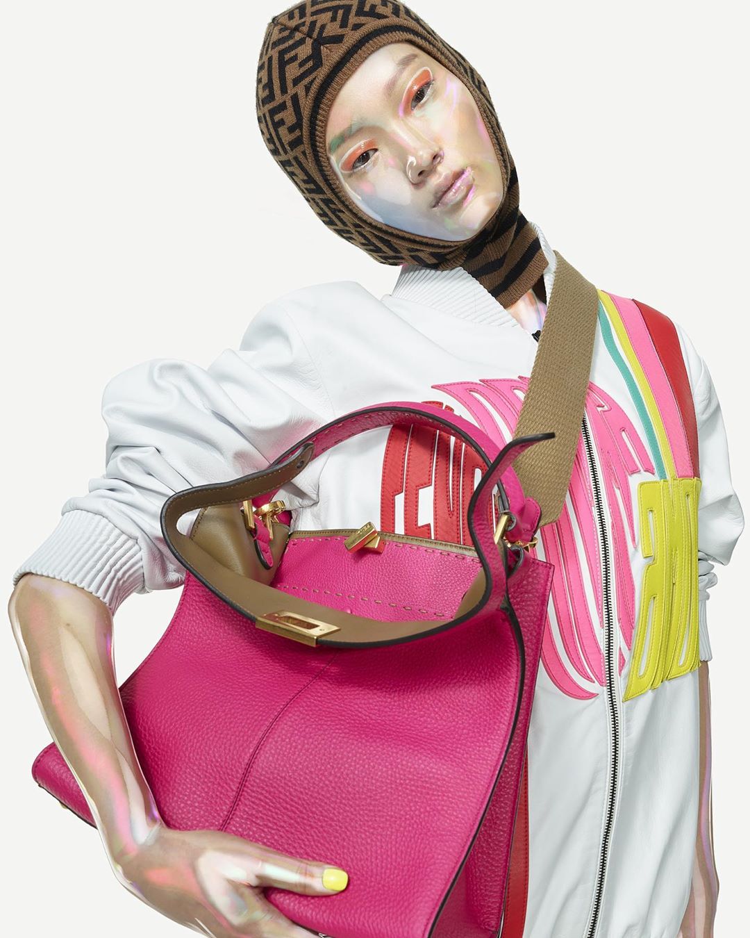 An adult female model poses with a hot pink leather purse. The photo has studio lighting and an isolated white background.