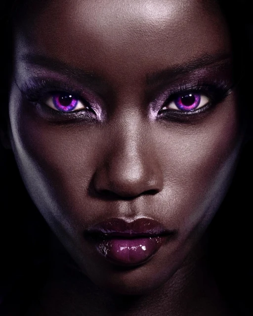 Close-up portrait of a woman with dark skin and purple makeup on her eyes and lips against a dark backdrop, beauty and fashion.