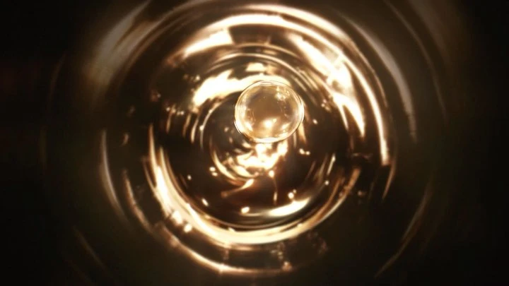 Abstract tunnel view with a golden orb at the center, creating a sense of depth and focus in a swirling, metallic environment.