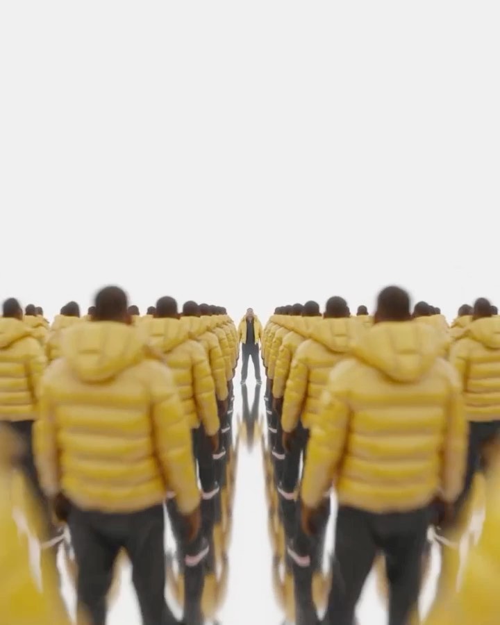 Numerous figures in yellow hooded jackets stand in rows on a reflective surface against a bright white background, creating a symmetrical visual.