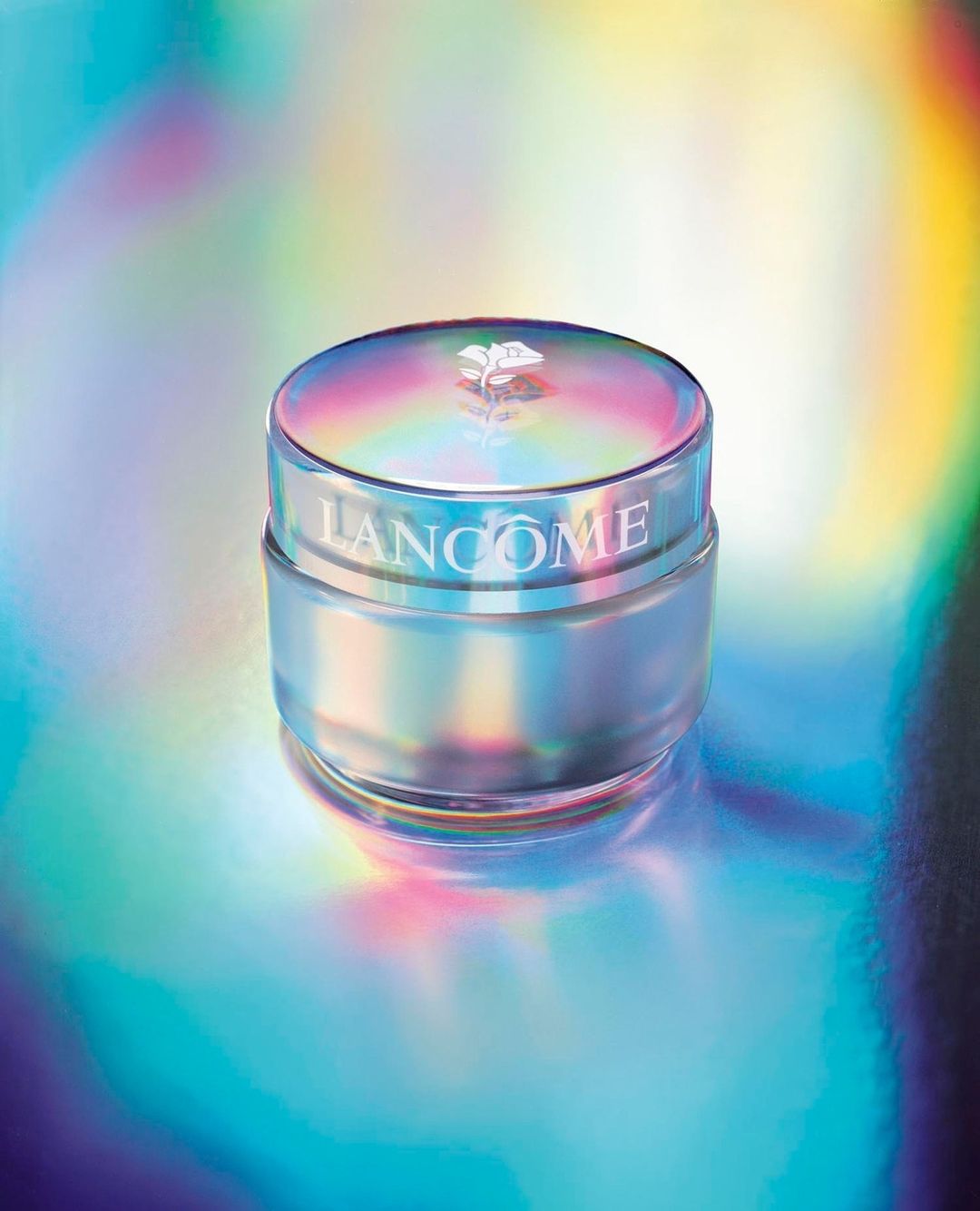 Lancome skincare product jar on a reflective iridescent surface, showcasing beauty and cosmetic product photography.