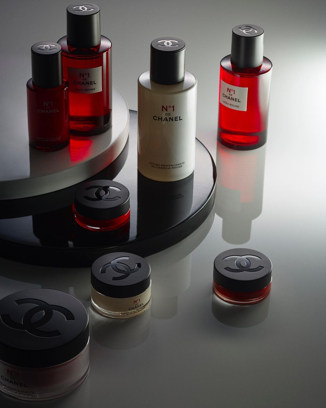A curated arrangement of Chanel No. 1 de Chanel skincare and fragrance products, featuring sleek bottles and jars with black lids.