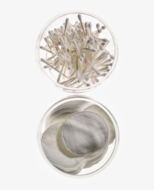 Overhead shot: Cotton swabs and cotton pads arranged in clear jars against a bright white backdrop, ideal for beauty or healthcare themes.