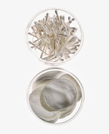 Overhead shot: Cotton swabs and cotton pads arranged in clear jars against a bright white backdrop, ideal for beauty or healthcare themes.