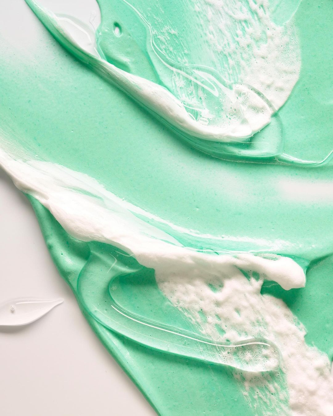 Textured shot of light turquoise and white cream, swirled and layered, creating a visually appealing and textured abstract pattern.