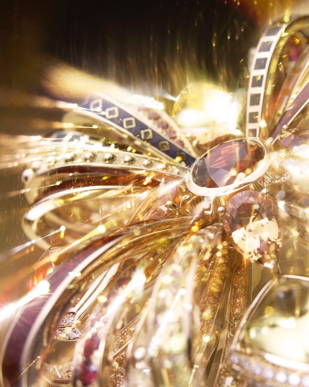 Close-up of an ornate golden bow with jewel accents, shimmering with light, suggesting high-end jewelry, luxury fashion accessory, or festive decoration.