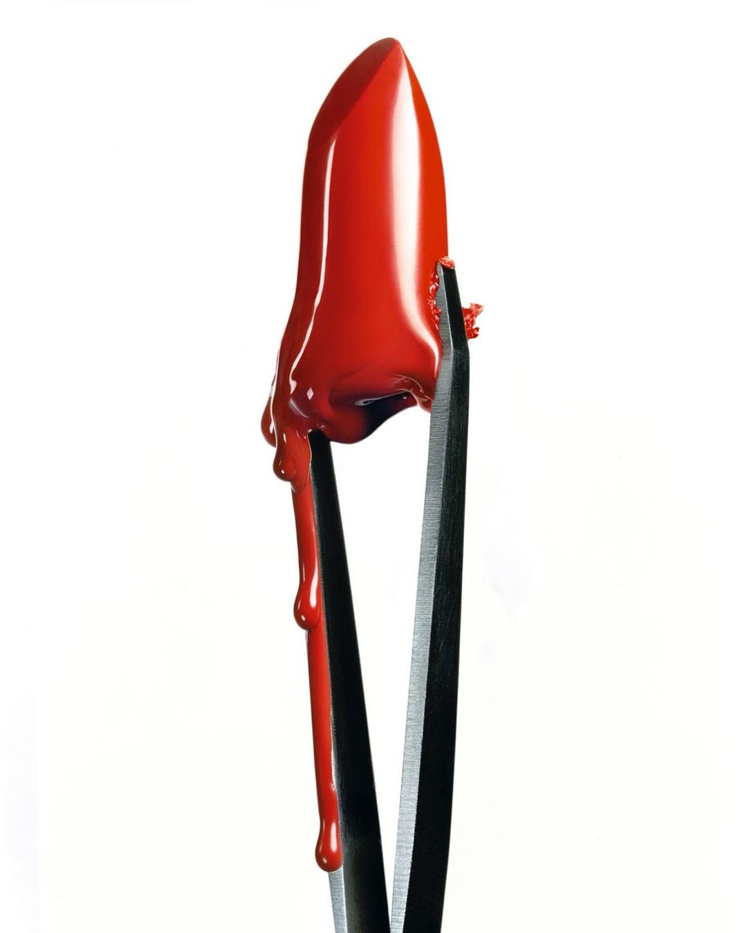 Close-up studio shot of bright red lipstick dripping and held by metal tweezers against a clean white background, dramatic beauty.