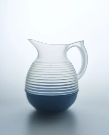 Studio shot of a clear glass pitcher with blue base and grooved design, set against a bright, neutral backdrop showcasing minimalist design.