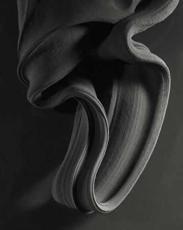 Abstract gray fabric drapes and swirls against a dark gray backdrop, creating a textured, monochrome artistic composition.