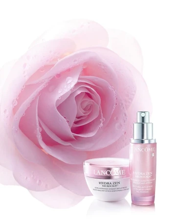 Close-up commercial product shot of Lancome Hydra Zen skincare bottles with a dew-covered pink rose against a clean white background